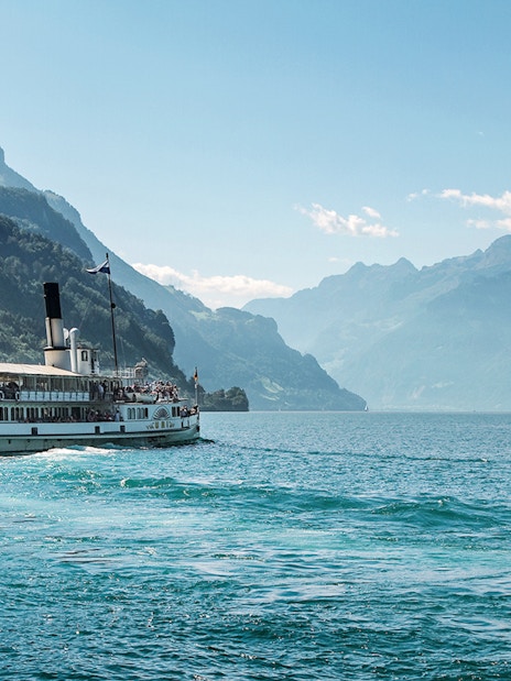 Steamboat on Lake Brienz with Swiss flag, surrounded by mountains in Berner Oberland.