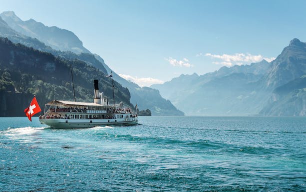 Steamboat on Lake Brienz with Swiss flag, surrounded by mountains in Berner Oberland.