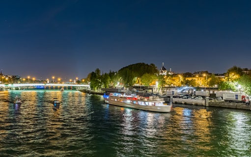Seine River cruise boat at night with city lights in Paris.