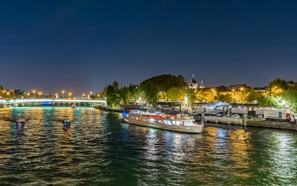 Seine River cruise boat at night with city lights in Paris.