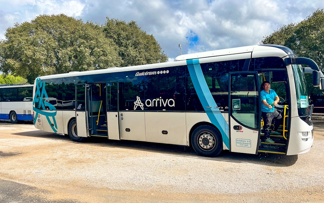 Bus for transfers to Krka National Park with driver at the door.