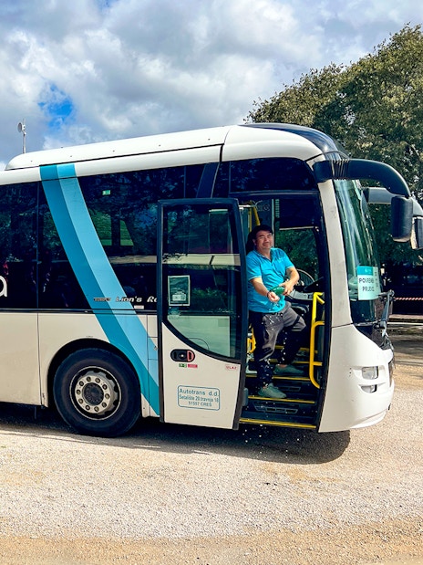 Bus for transfers to Krka National Park with driver at the door.