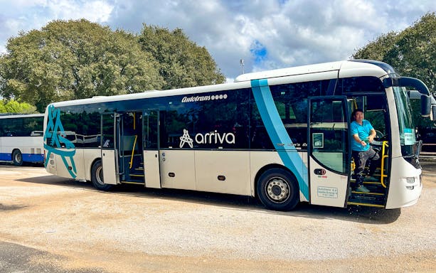 Bus for transfers to Krka National Park with driver at the door.