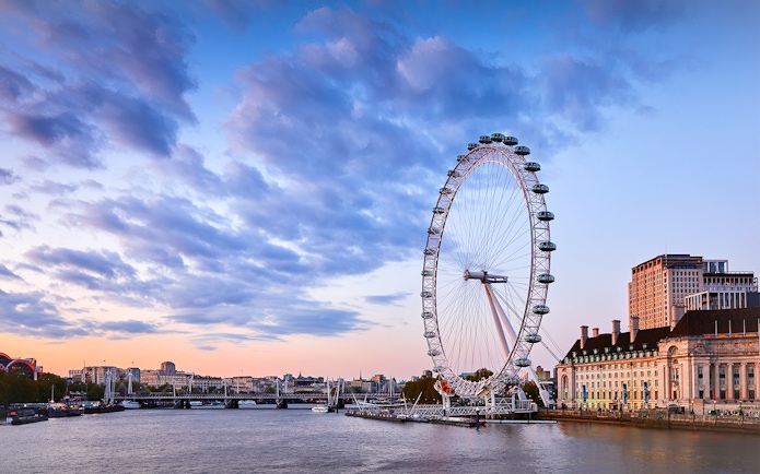 London Eye overlooking the Thames River at sunset.