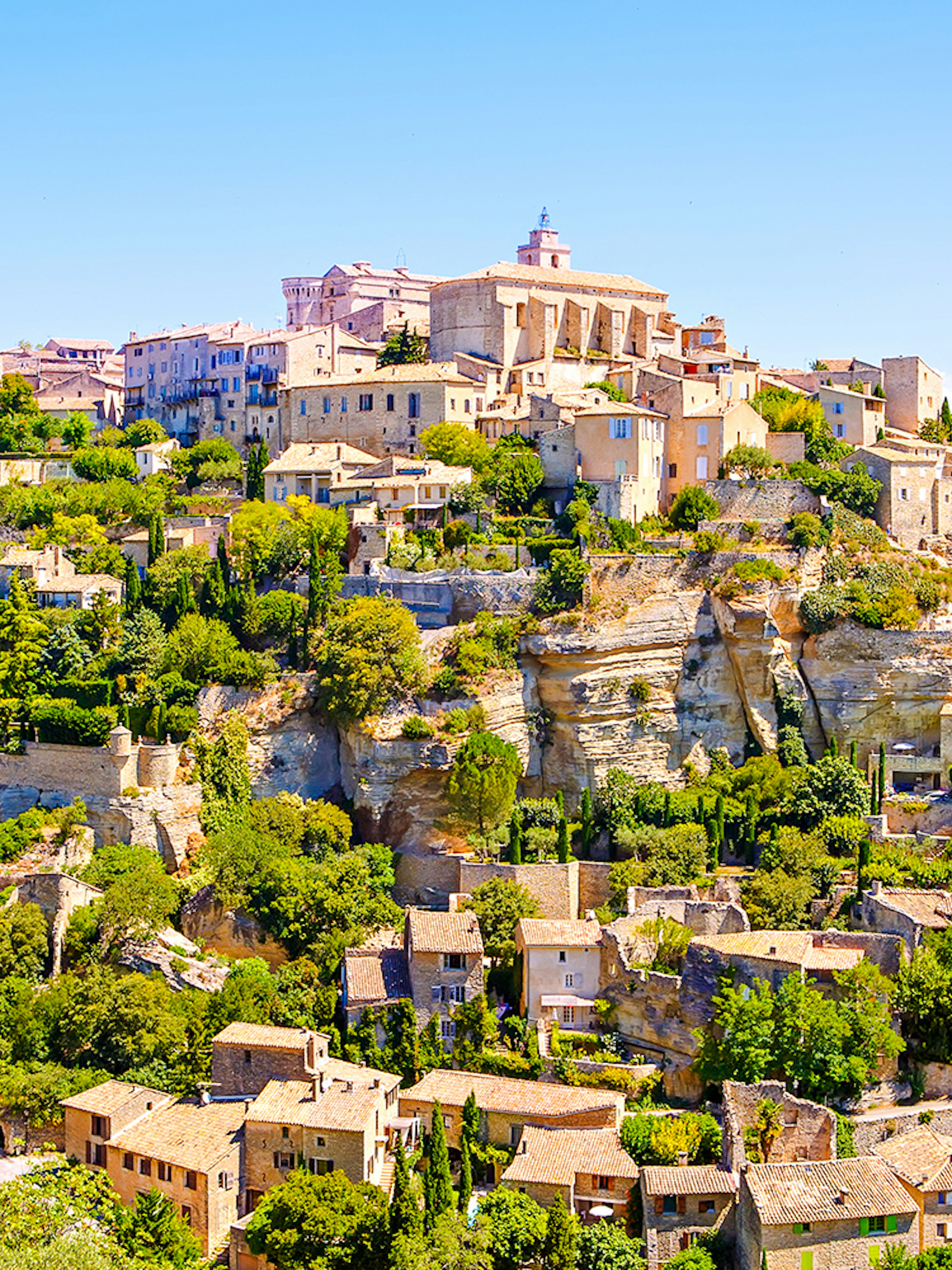Gordes village view with stone buildings and lush greenery in Provence, France.