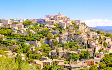 Gordes village view with stone buildings and lush greenery in Provence, France.