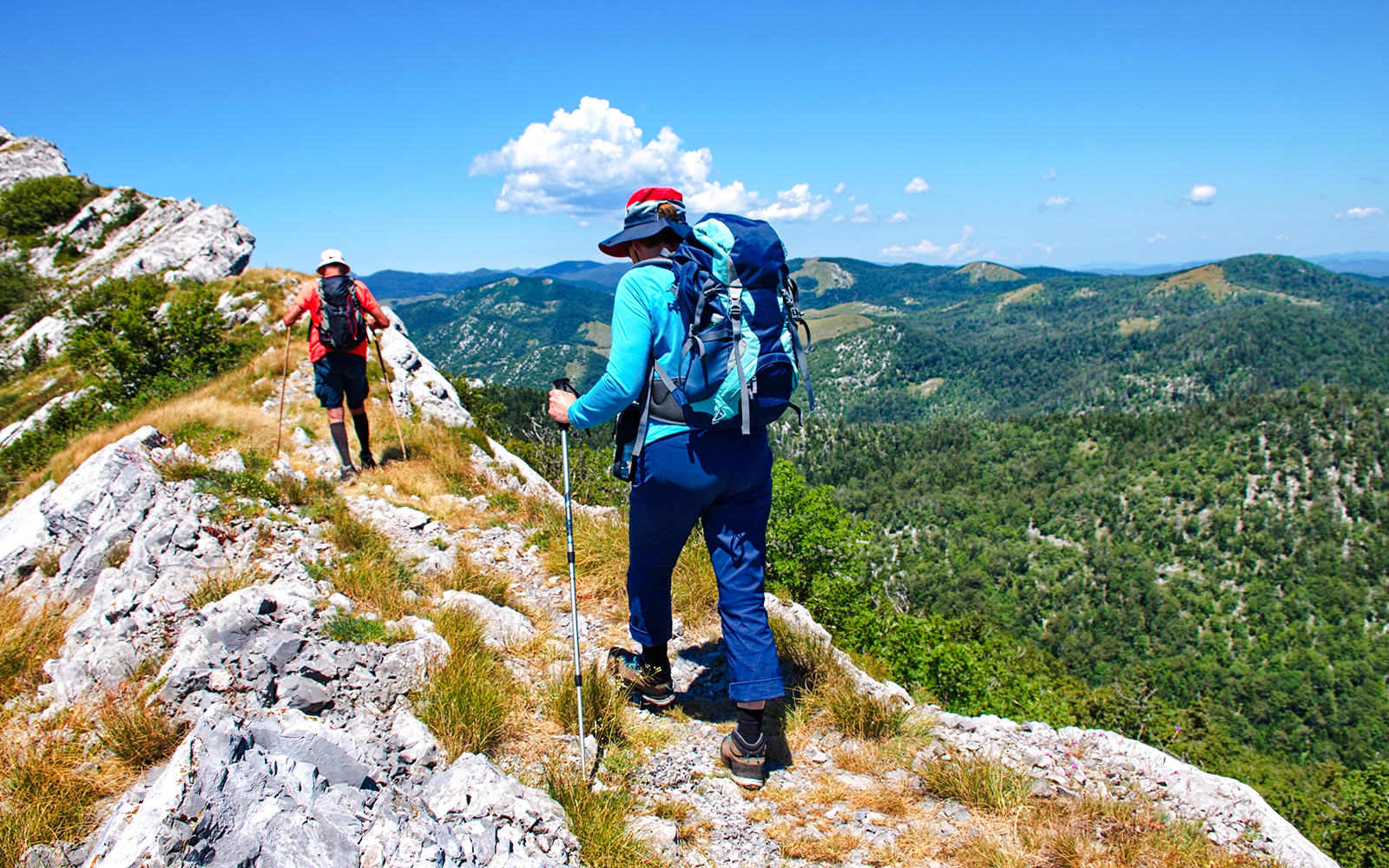 Couple hiking along rocky trail in Velebit mountain, Croatia.