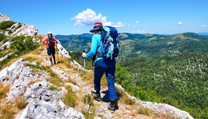 Couple hiking along rocky trail in Velebit mountain, Croatia.