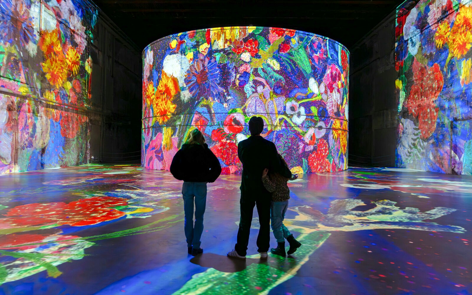 Visitors viewing vibrant Matisse artwork projections at Bassins des Lumières exhibition.