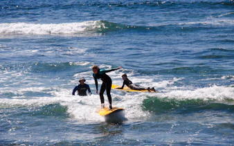 Beginner surfers learning on small waves in Taghazout with equipment.