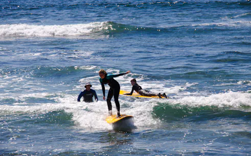 Beginner surfers learning on small waves in Taghazout with equipment.