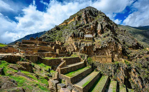 Terraced ruins in the Sacred Valley near Cusco, Peru, with stone structures and mountain backdrop.