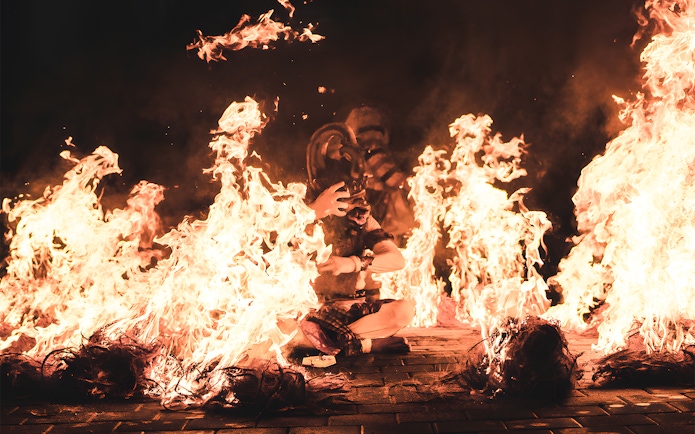 Kecak dancer surrounded by fire during a performance by the beach.