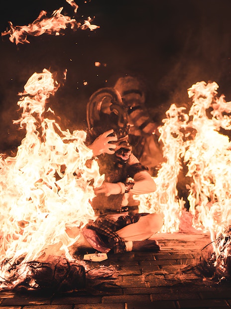 Kecak dancer surrounded by fire during a performance by the beach.