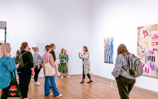 Group listening to a guide inside Tate Modern gallery.