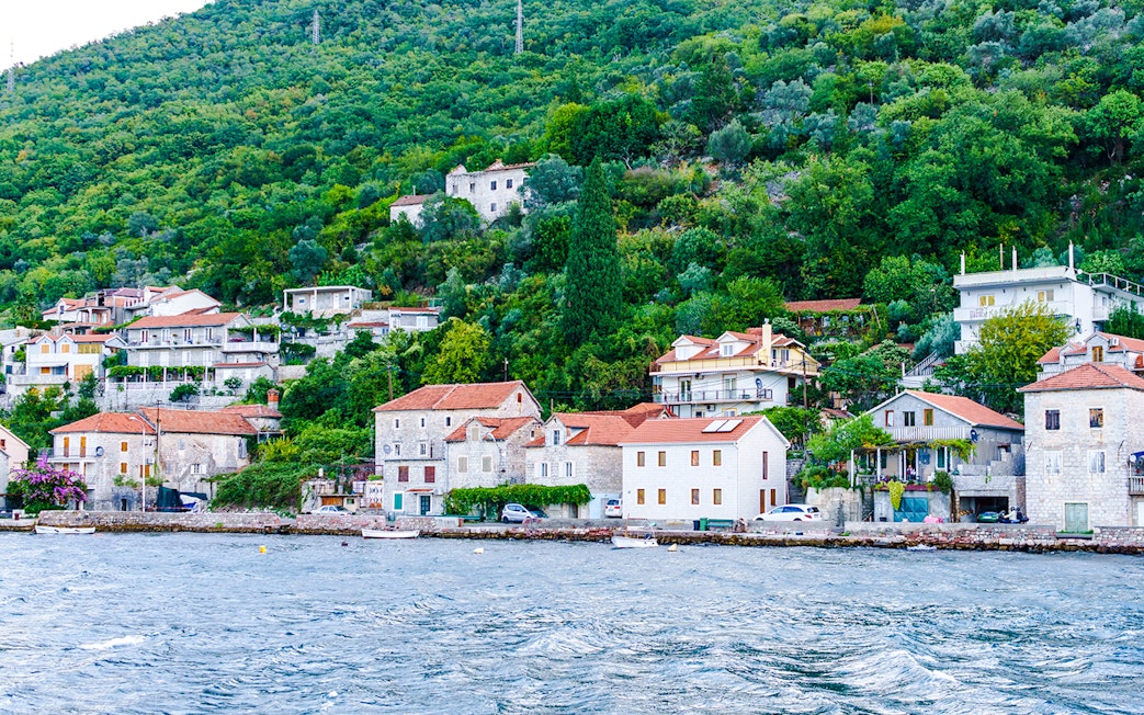 Fisherman's village with stone houses along Kotor Bay shoreline.