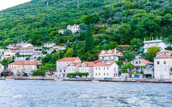 Fisherman's village with stone houses along Kotor Bay shoreline.
