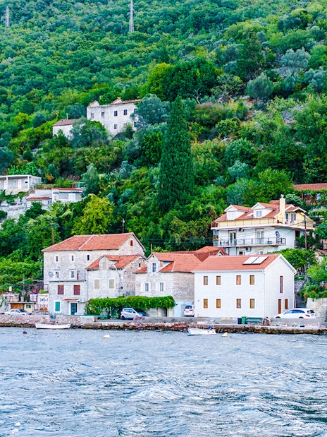 Fisherman's village with stone houses along Kotor Bay shoreline.