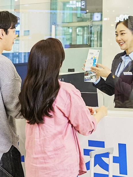 Couple receiving travel information at Incheon Airport counter for Seoul Station trip.