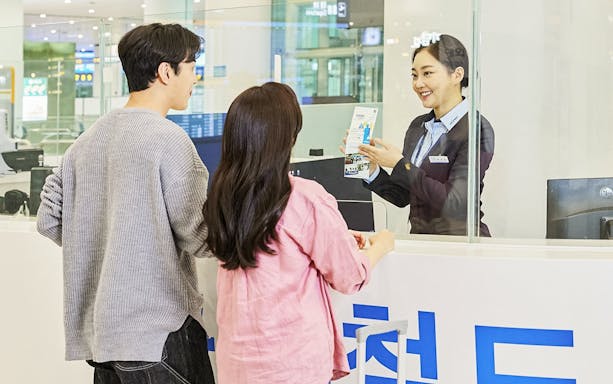 Couple receiving travel information at Incheon Airport counter for Seoul Station trip.