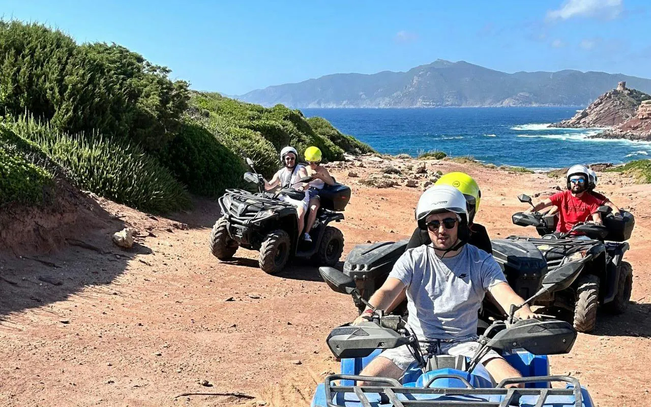 Quad bikers on a dirt trail near Lake Baratz and Porto Ferro, Alghero, with coastal views.