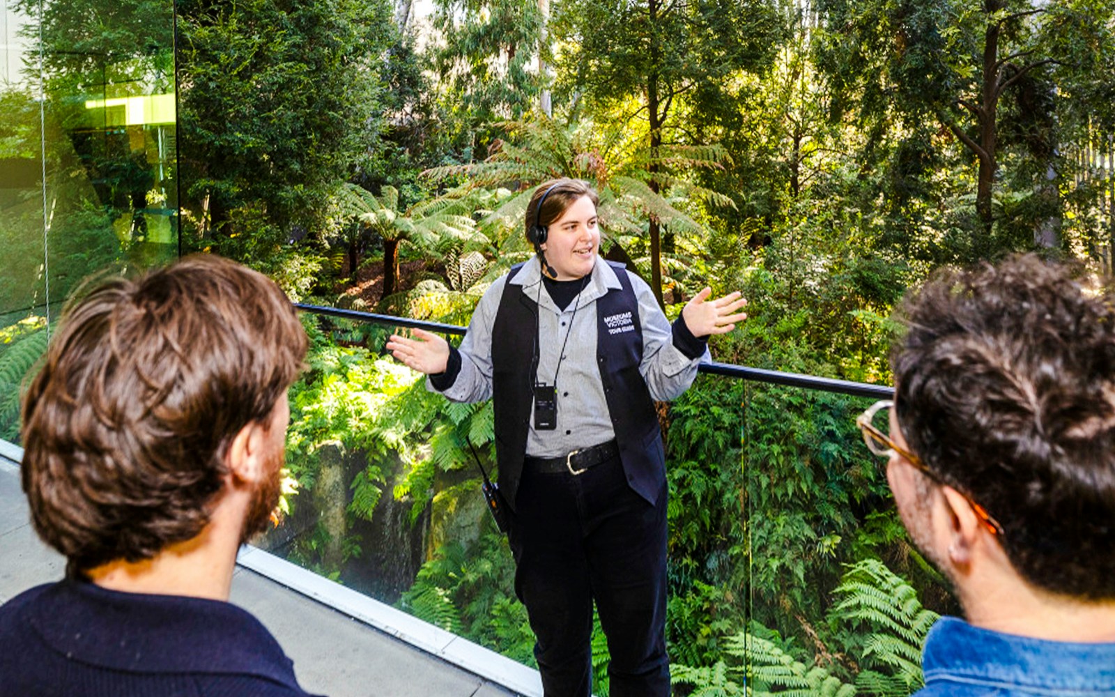 Tour guide leading visitors through indoor forest at Melbourne Museum.