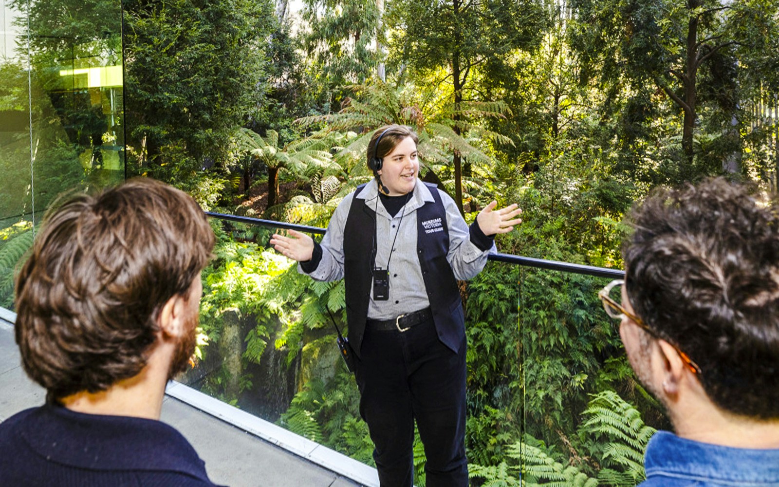 Tour guide leading visitors through indoor forest at Melbourne Museum.