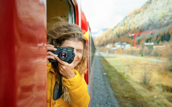 Woman taking photos from the Red Train to Alp Grum, Switzerland.