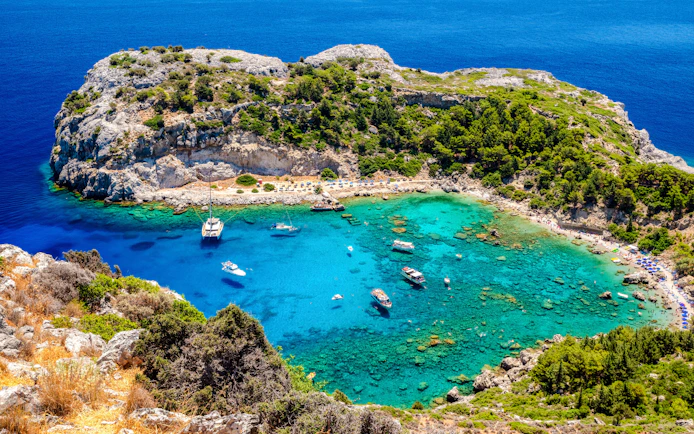 Boats anchored in the turquoise waters of Anthony Quinn Bay, Rhodes Island, Greece.