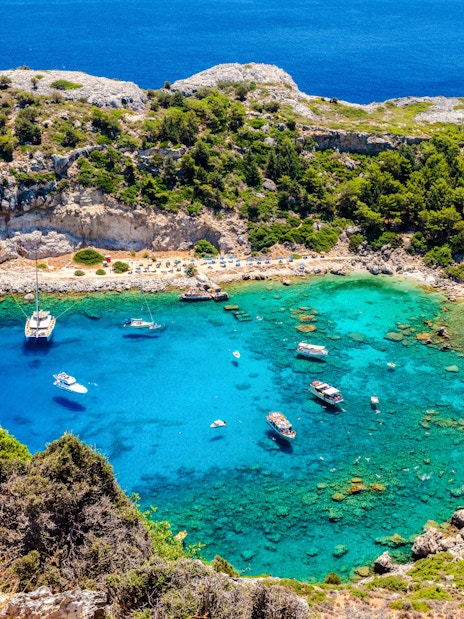 Boats anchored in the turquoise waters of Anthony Quinn Bay, Rhodes Island, Greece.