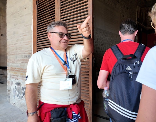 Guide leading tourists through Pompeii ruins.