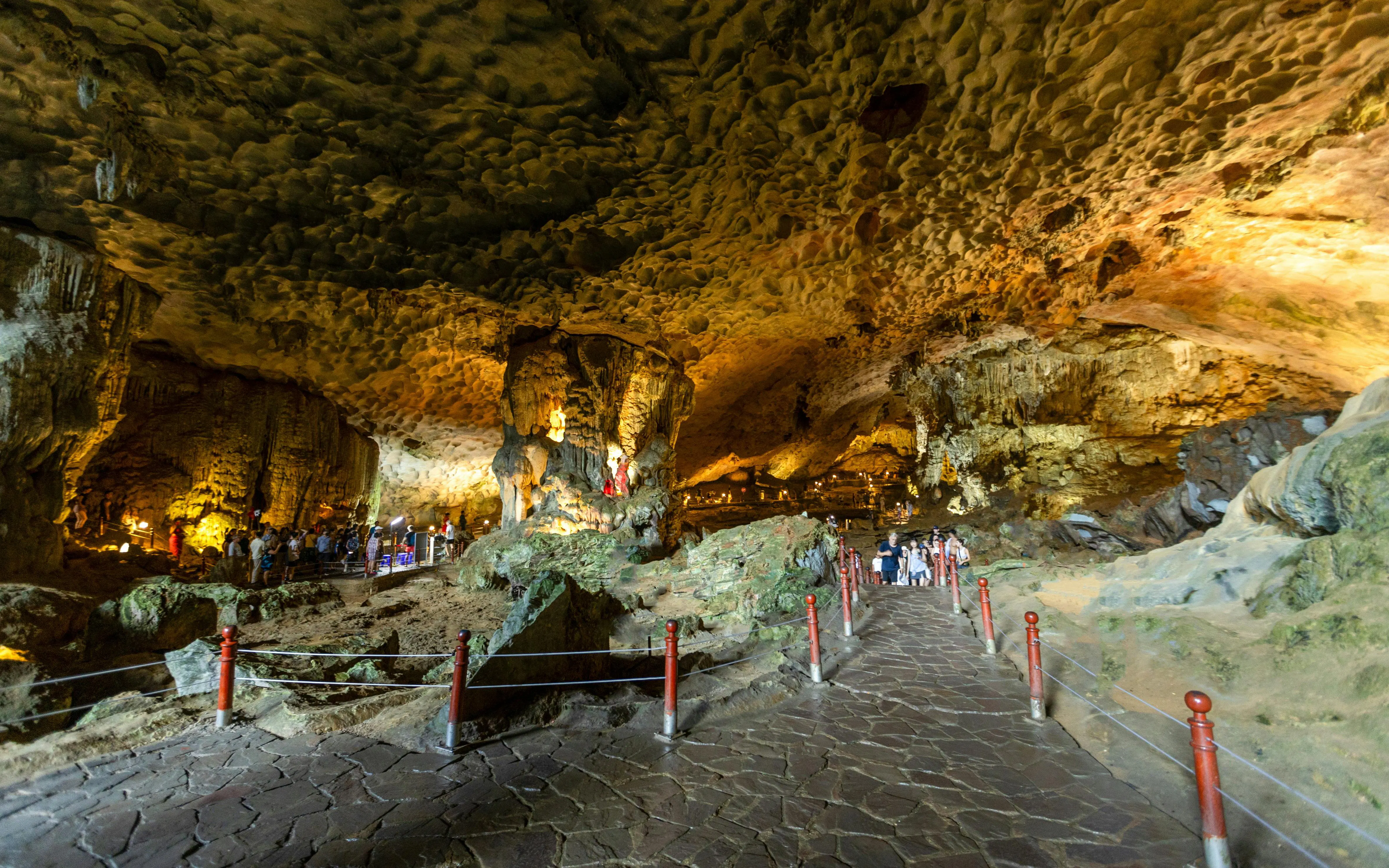 Hang Sung Sot Cave interior with tourists exploring limestone formations in Ha Long Bay, Vietnam.