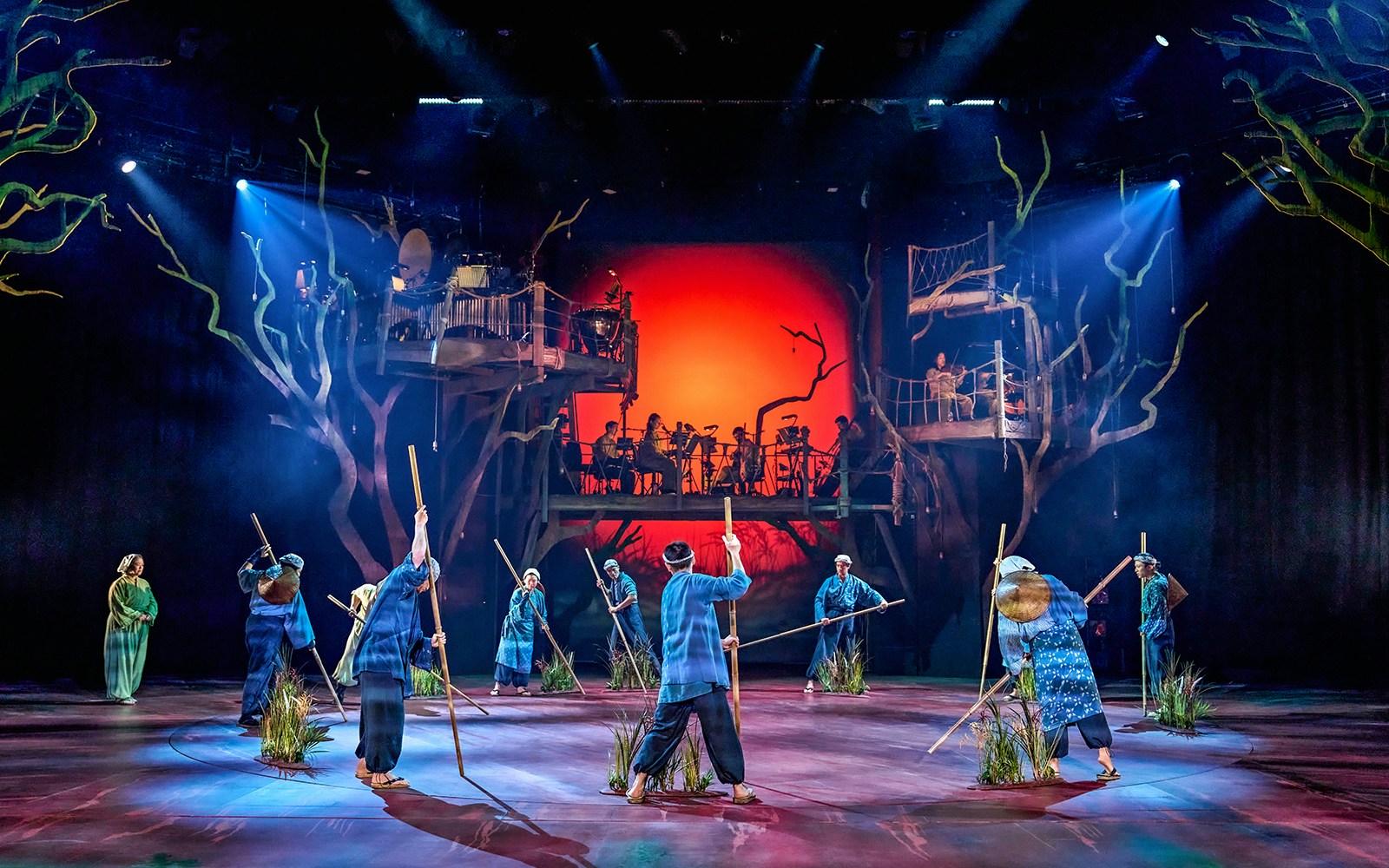 Stage performance of My Neighbour Totoro with actors holding sticks, vibrant backdrop.