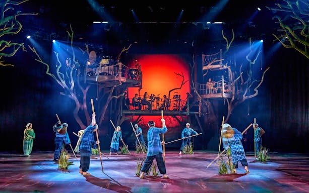 Stage performance of My Neighbour Totoro with actors holding sticks, vibrant backdrop.