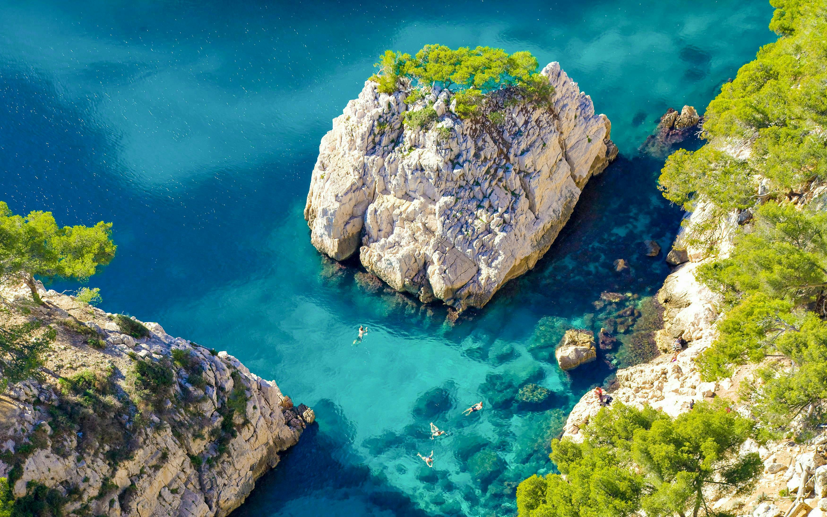 Excursion boats cruising in Calanques de Cassis, France, with clear turquoise waters and rocky cliffs.