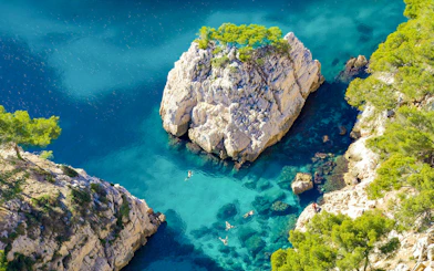 Excursion boats cruising in Calanques de Cassis, France, with clear turquoise waters and rocky cliffs.