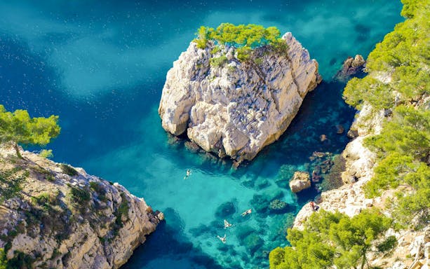Excursion boats cruising in Calanques de Cassis, France, with clear turquoise waters and rocky cliffs.