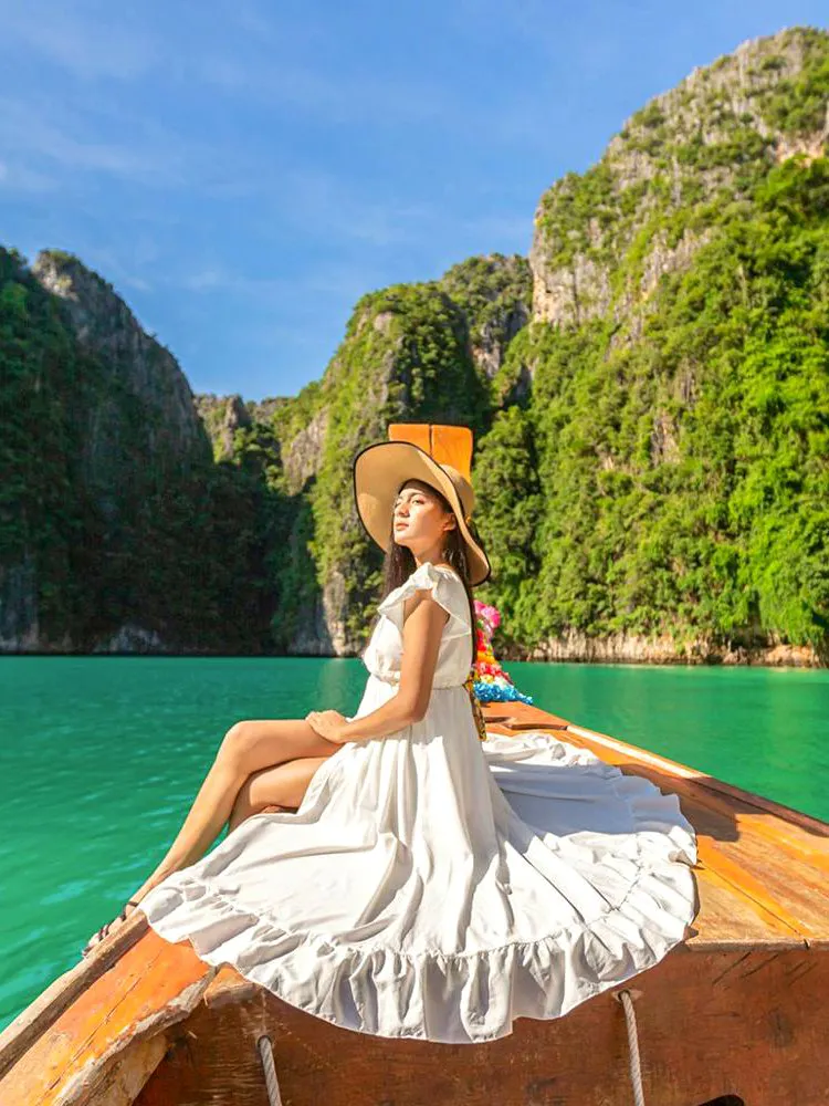 Woman in white dress on longtail boat, Maya Bay tour, Phi Phi Islands.