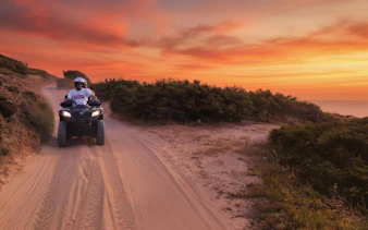 Quad biking at sunset on a sandy trail in Santa Teresa di Gallura, Olbia.