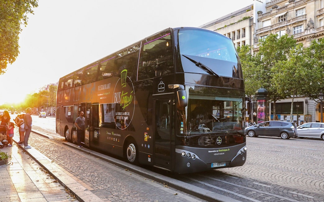 Double-decker Bus Toqué in Paris with passengers boarding at sunset.