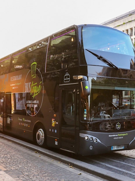 Double-decker Bus Toqué in Paris with passengers boarding at sunset.