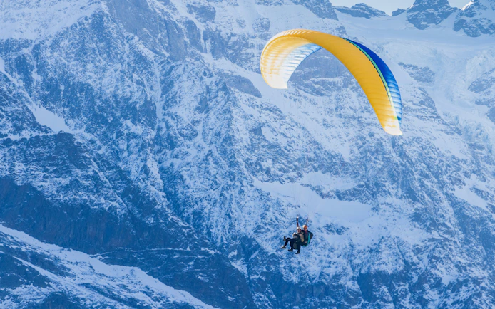 Paragliders soaring over snowy mountains in Interlaken.