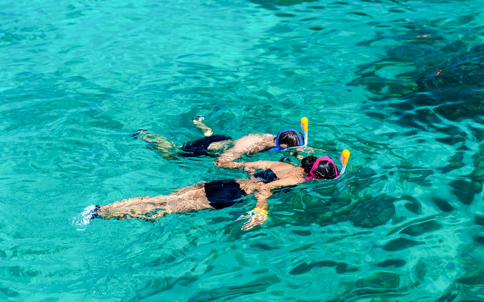 Two people snorkeling in clear Surin Islands waters.