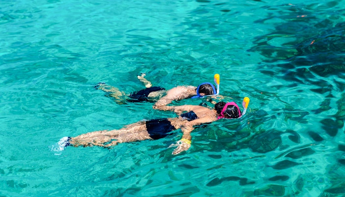 Two people snorkeling in clear Surin Islands waters.