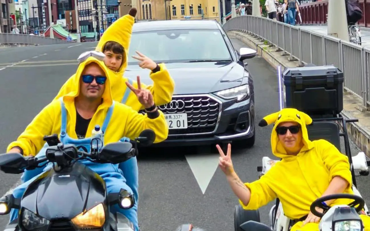 Go-kart riders in costume on a street in Asakusa, Tokyo, with Skytree in the background.