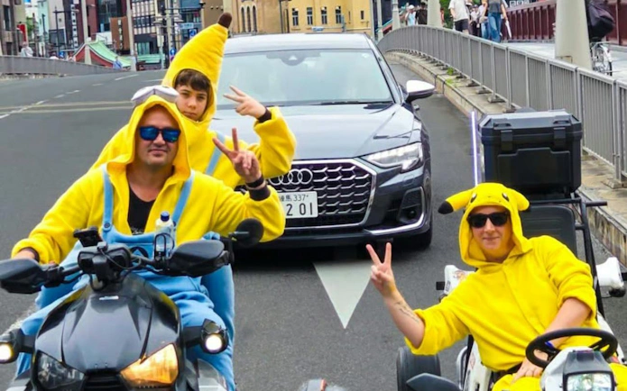 Go-kart riders in costume on a street in Asakusa, Tokyo, with Skytree in the background.