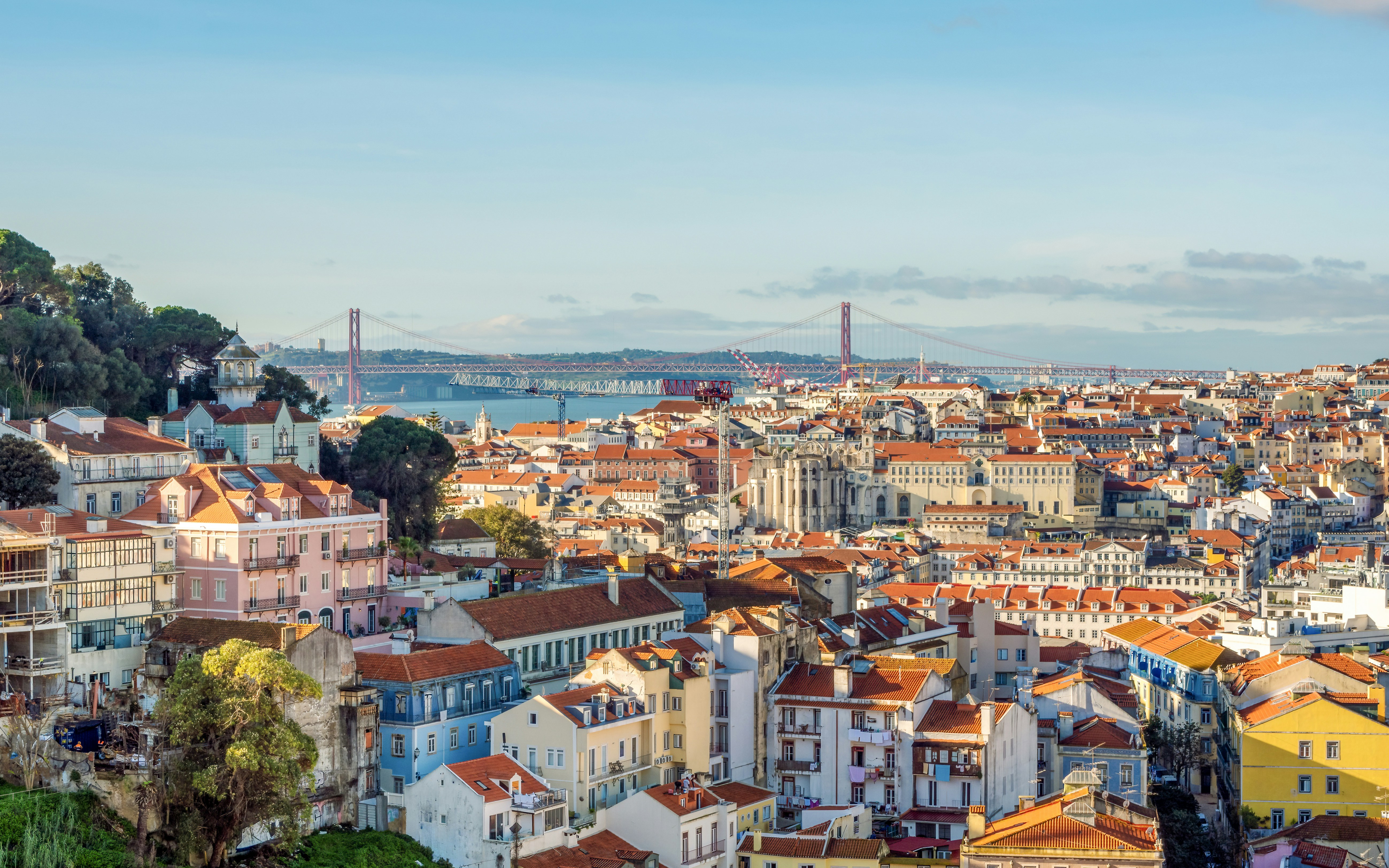 Panoramic view of Lisbon with colorful buildings and 25 de Abril Bridge from Miradouro da Graça.