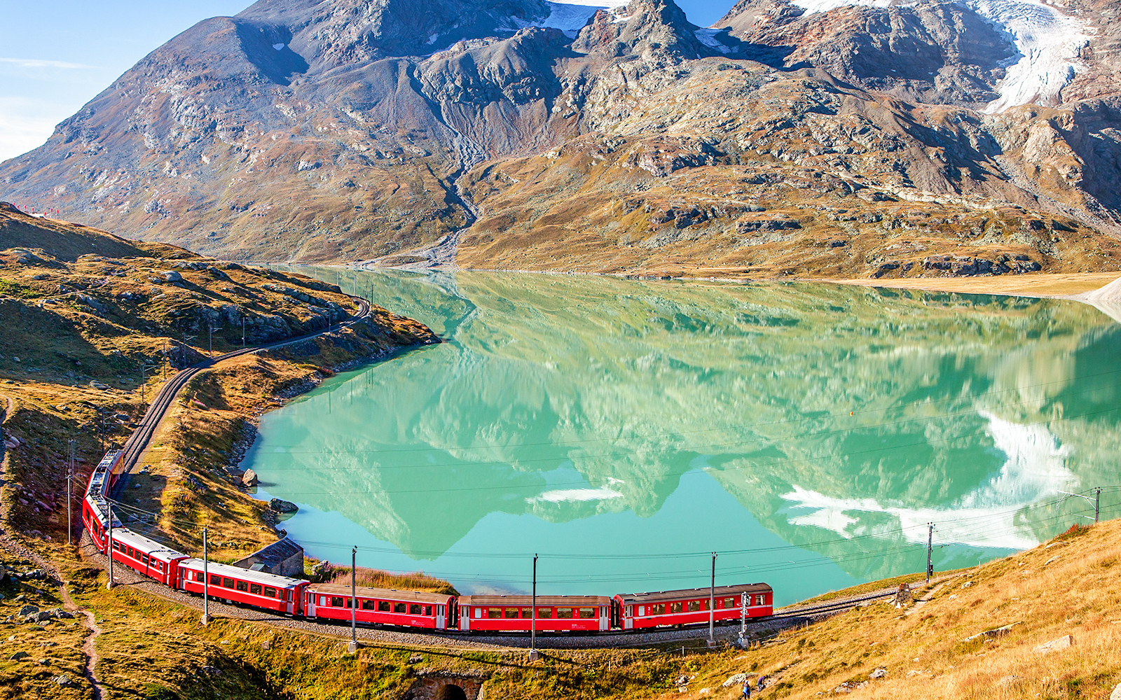 Glacier Express during spring season in front of a blue clear meadow