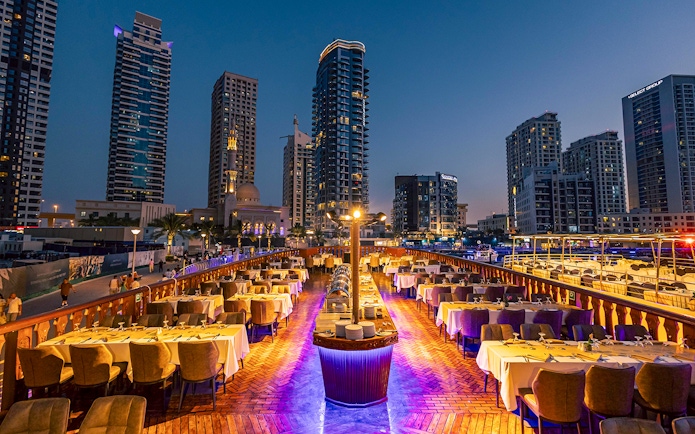 Dhow cruise dinner setup with cityscape view at Dubai Marina.