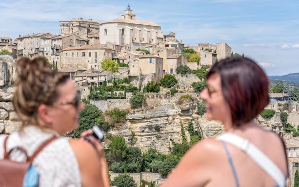Provence village view with historic stone buildings and tourists in foreground.